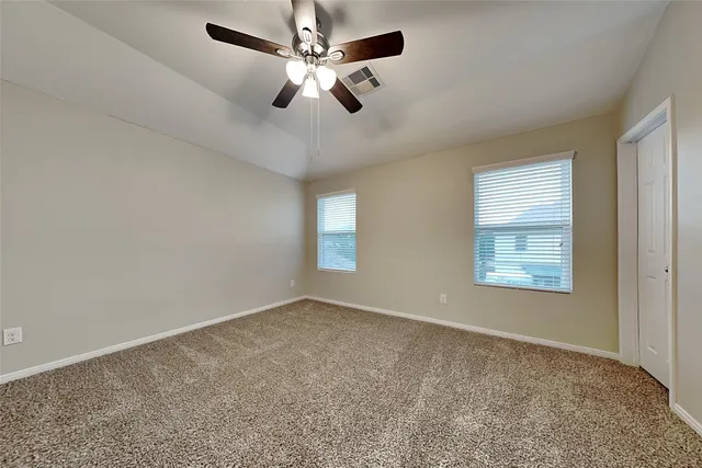 en empty room with windows and ceiling fan