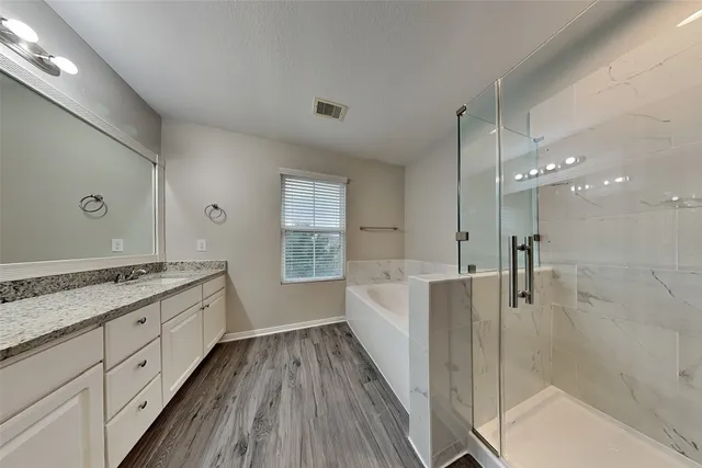 a bathroom with a granite countertop double vanity sink a mirror and a bathtub