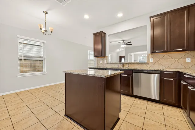 a kitchen with kitchen island granite countertop a sink cabinets and stainless steel appliances
