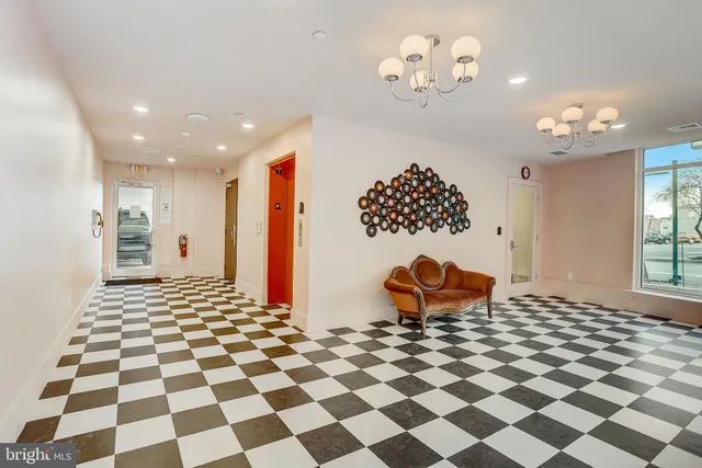 a living room with a black white checkered floor with a gaming machine and dining table