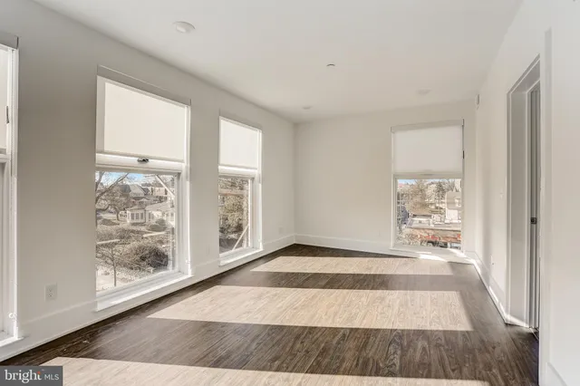 a view of an empty room with window and wooden floor