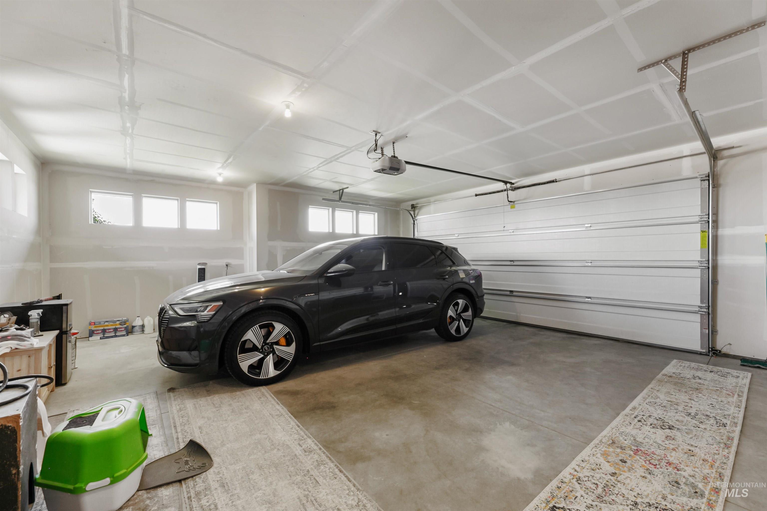 24398 Tombstone Ridge Court Middleton, ID 83644 - Photo 42 of 47 Spacious garage featuring a concrete floor, high ceilings, multiple transom windows, an automatic garage door opener, and a wall-mounted electric vehicle charging station