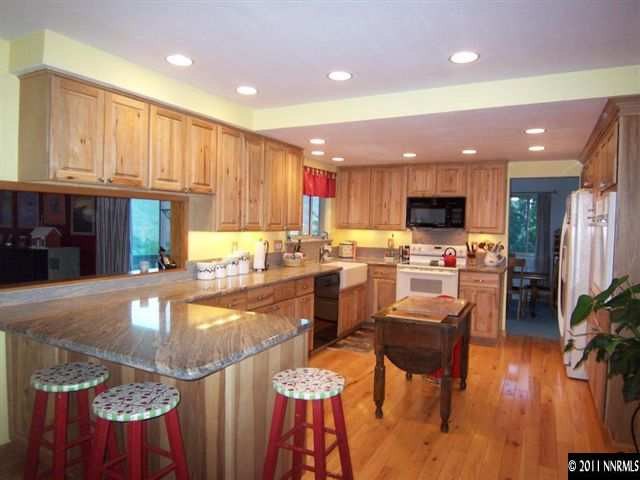20710 Cooke Drive Reno, NV 89521 - Photo 6 of 13 a kitchen with stainless steel appliances granite countertop a refrigerator a sink dishwasher a stove and white cabinets with wooden floor