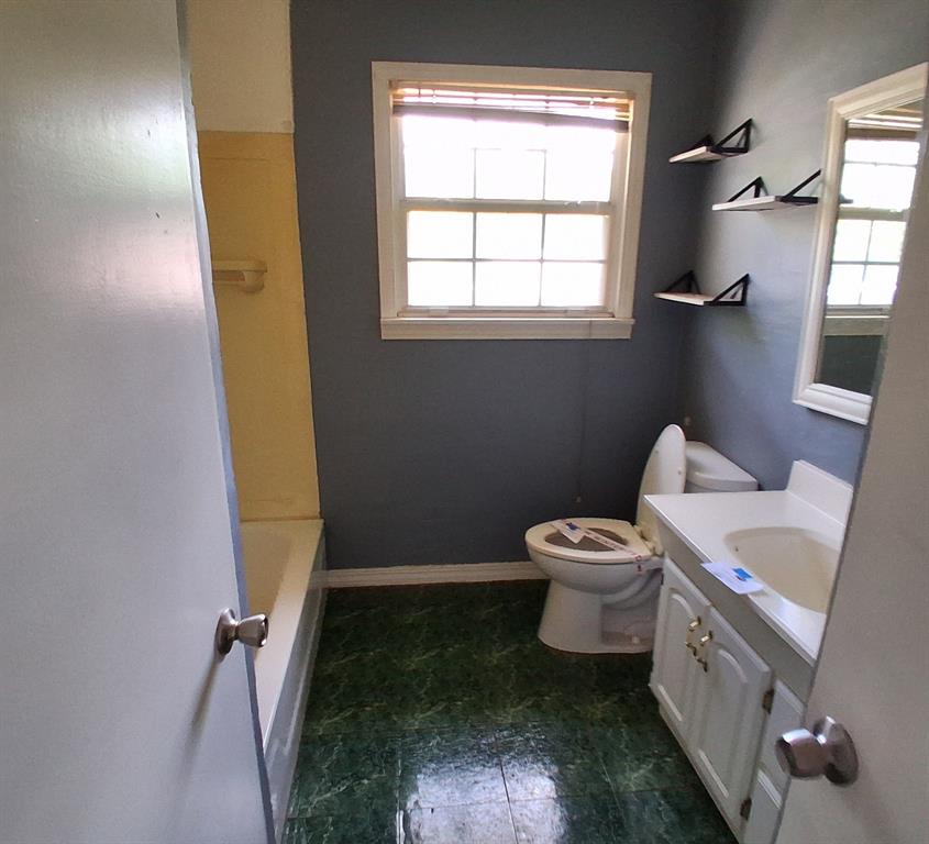 910 Success Street Gilmer, TX 75644 - Photo 15 of 20 a bathroom with a granite countertop sink a toilet and a mirror