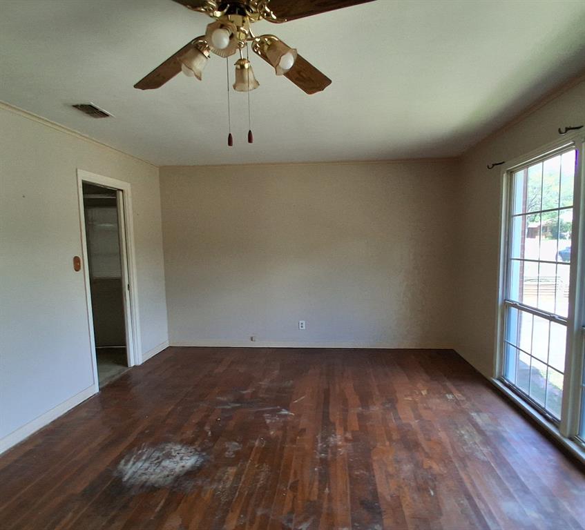 910 Success Street Gilmer, TX 75644 - Photo 4 of 20 an empty room with wooden floor chandelier fan and windows