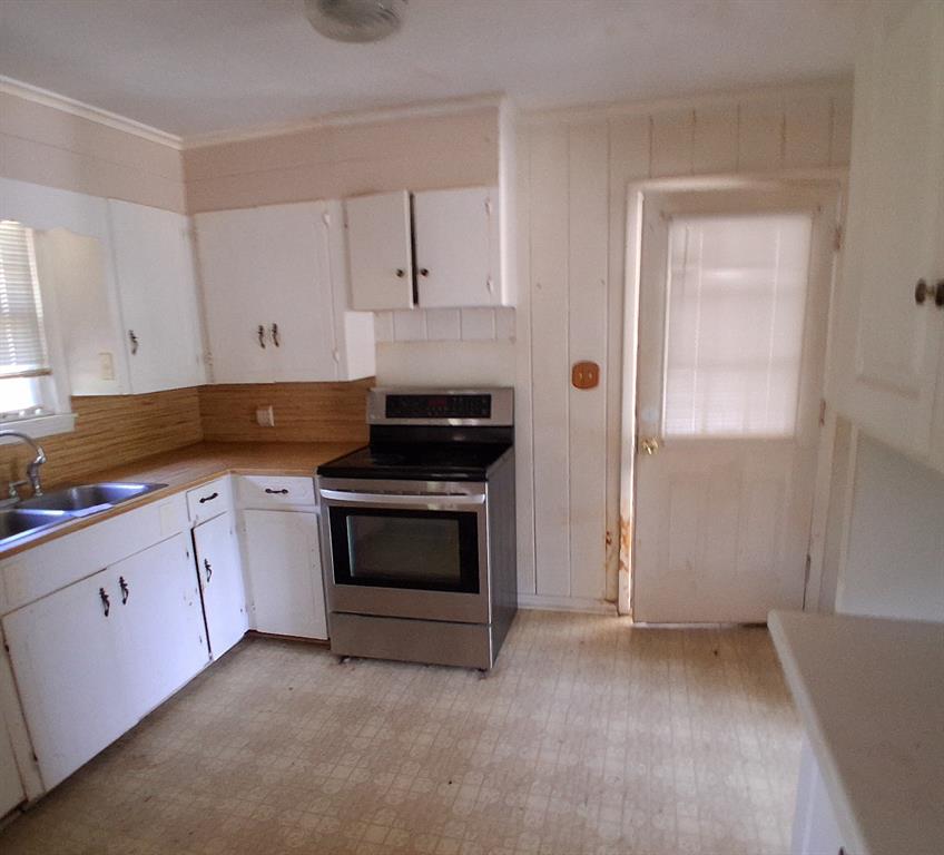 910 Success Street Gilmer, TX 75644 - Photo 10 of 20 a kitchen with granite countertop white cabinets and stainless steel appliances