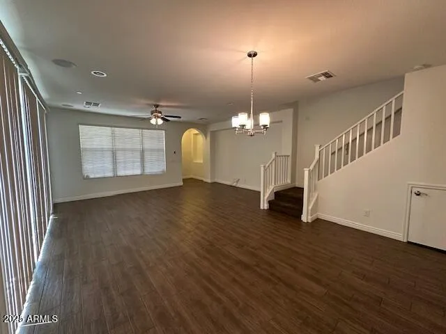 an empty room with wooden floor chandelier and windows