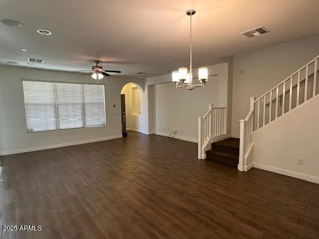 an empty room with wooden floor chandelier and windows
