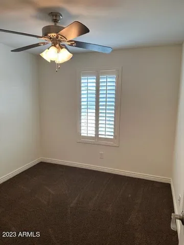 an empty room with a chandelier fan and windows