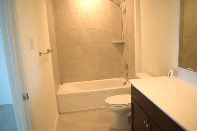 a bathroom with a granite countertop bathtub shower sink vanity and toilet
