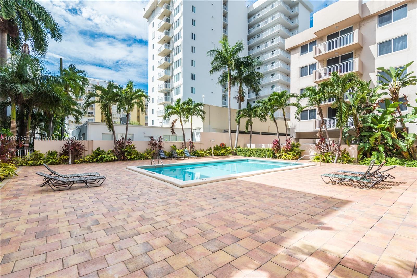 1665 Bay Road, Unit 425 Miami Beach, FL 33139 - Photo 2 of 15 a view of a swimming pool with a chair and palm trees