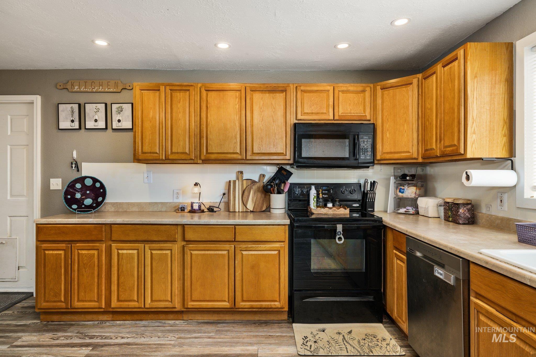 1504 2nd Street North Nampa, ID 83687 - Photo 11 of 29 Kitchen featuring black appliances, wood finish cabinets, light countertops, wood finished floors, and recessed lighting