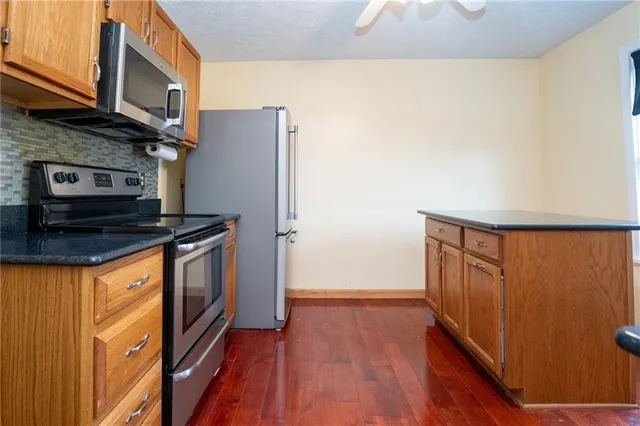 a kitchen with granite countertop a refrigerator a stove and wooden floor