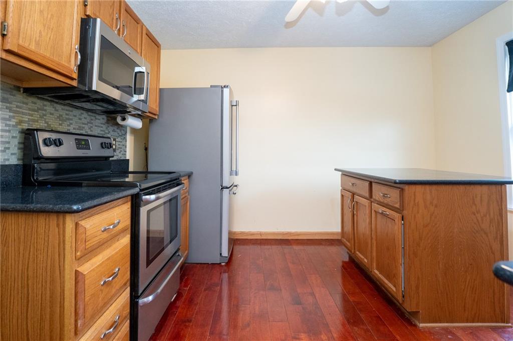 7324 Green Meadow Drive Imperial, PA 15126 - Photo 4 of 43 a kitchen with granite countertop a refrigerator a stove and wooden floor