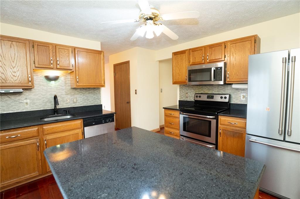 7324 Green Meadow Drive Imperial, PA 15126 - Photo 5 of 43 a kitchen with stainless steel appliances granite countertop a stove refrigerator sink and microwave