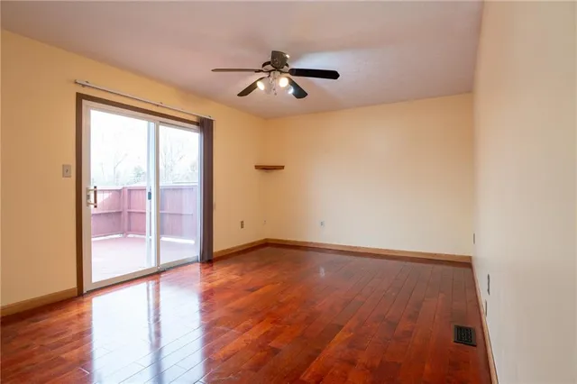 an empty room with wooden floor fan and windows