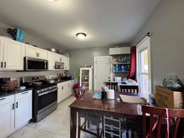 a kitchen with stainless steel appliances granite countertop a stove a refrigerator a sink dishwasher with a dining table and chairs