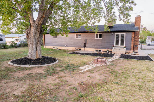 634 South 2100th Street West Vernal, UT 84078 - Photo 70 of 71 Spacious backyard featuring a large tree with a decorative mulch ring, a stone fire pit, and a flagstone pathway
