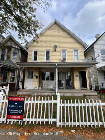 a view of a white house with large windows and a small yard