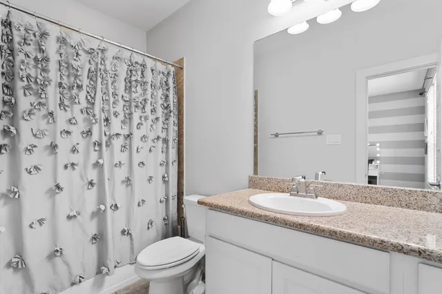 a bathroom with a granite countertop sink toilet and a mirror