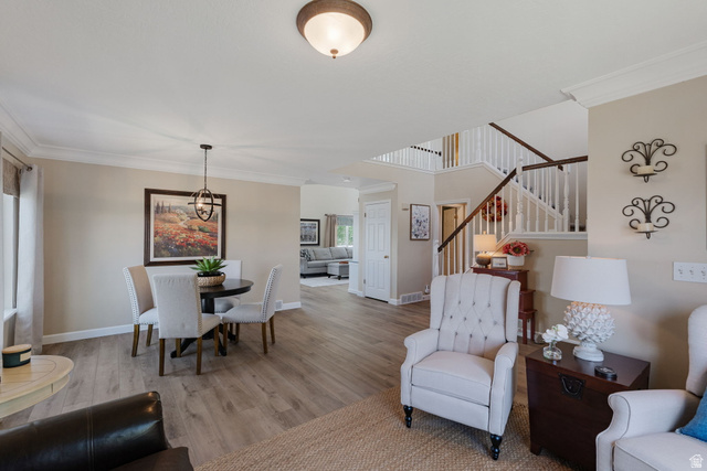 14883 Tooele Lane Draper, UT 84020 - Photo 14 of 49 Open-concept living area featuring wood-finish flooring, a two-story staircase with white balusters and wood handrails, crown molding, and recessed lighting