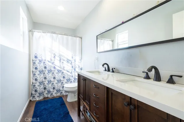 a bathroom with a double vanity sink toilet and a mirror
