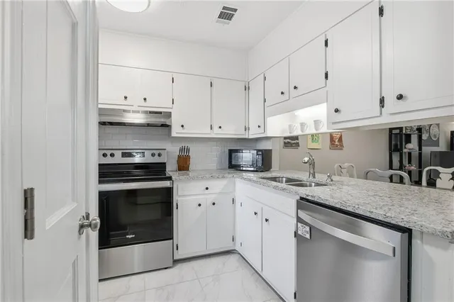 a kitchen with granite countertop white cabinets and white appliances