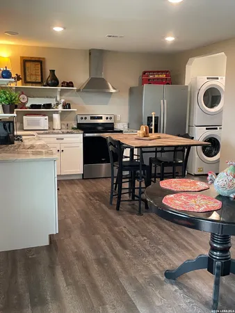 a kitchen with stainless steel appliances granite countertop a stove top oven a sink a dining table and chairs with wooden floor