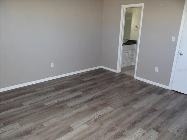 a view of an empty room with wooden floor and closet