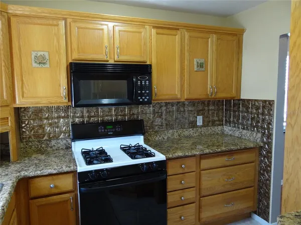 a kitchen with granite countertop cabinets stove and microwave