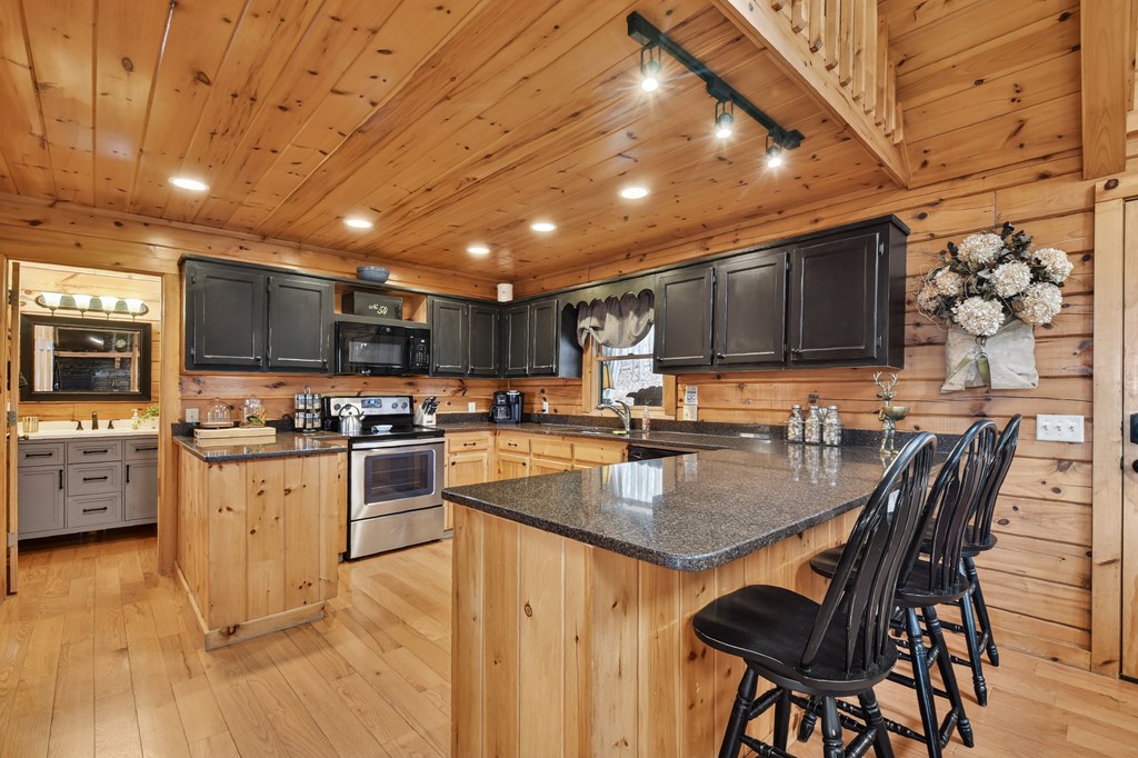 54 Channing Ridge Road Morganton, GA 30560 - Photo 29 of 54 a kitchen with stainless steel appliances granite countertop a stove top oven a sink dishwasher a dining table and chairs with wooden floor