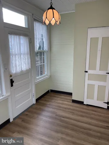 an empty room with wooden floor window and windows