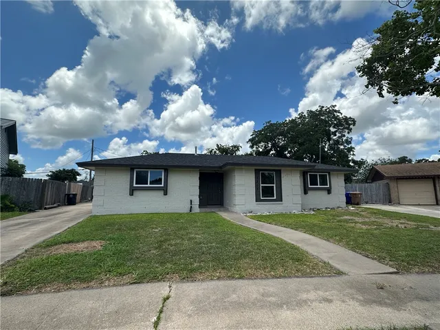 a view of a house with a yard and a large tree