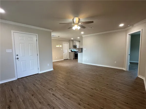 a view of empty room with wooden floor and ceiling fan