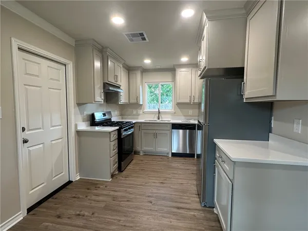 a kitchen with stainless steel appliances granite countertop a sink a stove a refrigerator cabinets and a kitchen island