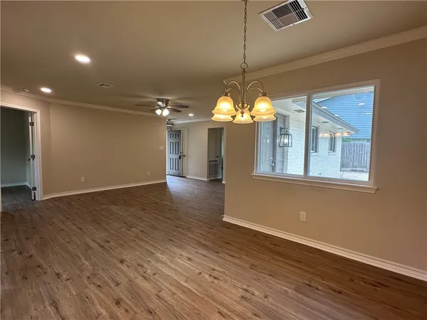 a view of a room with wooden floor chandelier and windows