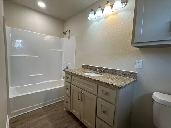 a bathroom with a granite countertop sink a toilet and bathtub
