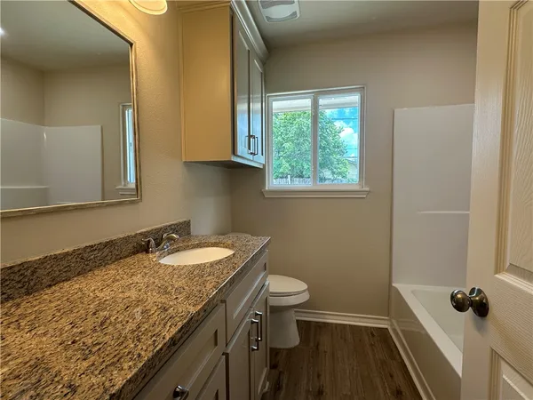 a bathroom with a granite countertop sink a mirror and a toilet