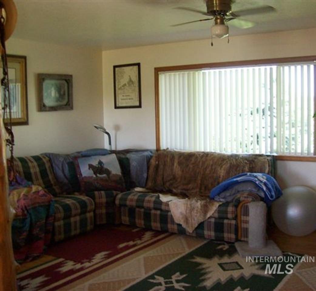 721 Mendiola Road Nyssa, OR 97913 - Photo 5 of 16 Living area with a large window featuring vertical blinds, a ceiling fan with integrated lighting, and light-toned walls