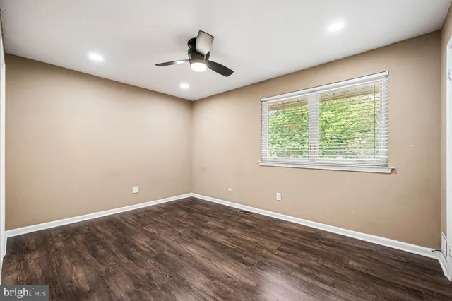 an empty room with wooden floor ceiling fan and window