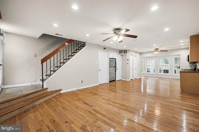 a view of empty room with wooden floor and fan