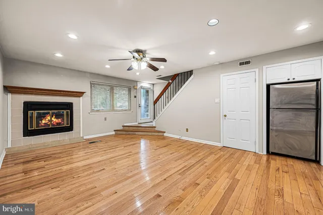 an empty room with wooden floor and a kitchen