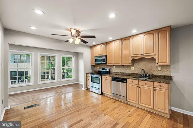 a large kitchen with granite countertop a stove top oven a sink and wooden floor