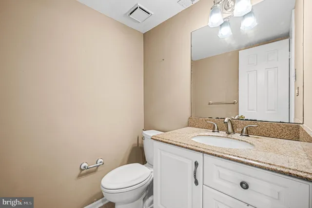 a bathroom with a granite countertop sink a toilet and a mirror