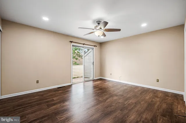an empty room with wooden floor chandelier fan and windows