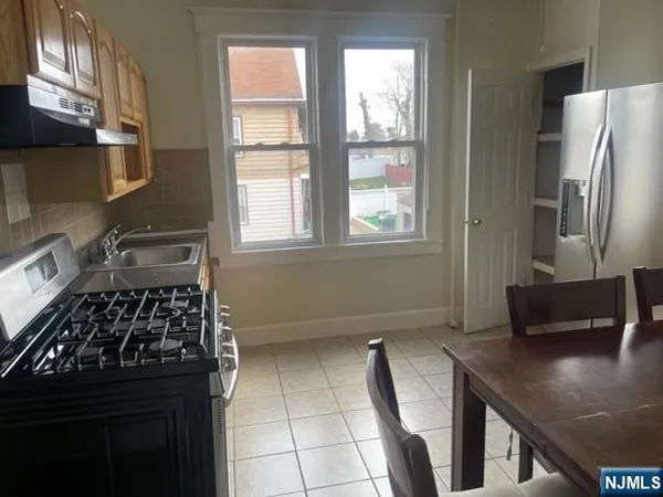 a kitchen with stainless steel appliances a stove a refrigerator a sink a counter space and cabinets
