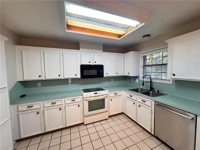 a kitchen with a refrigerator a stove top oven and white cabinets