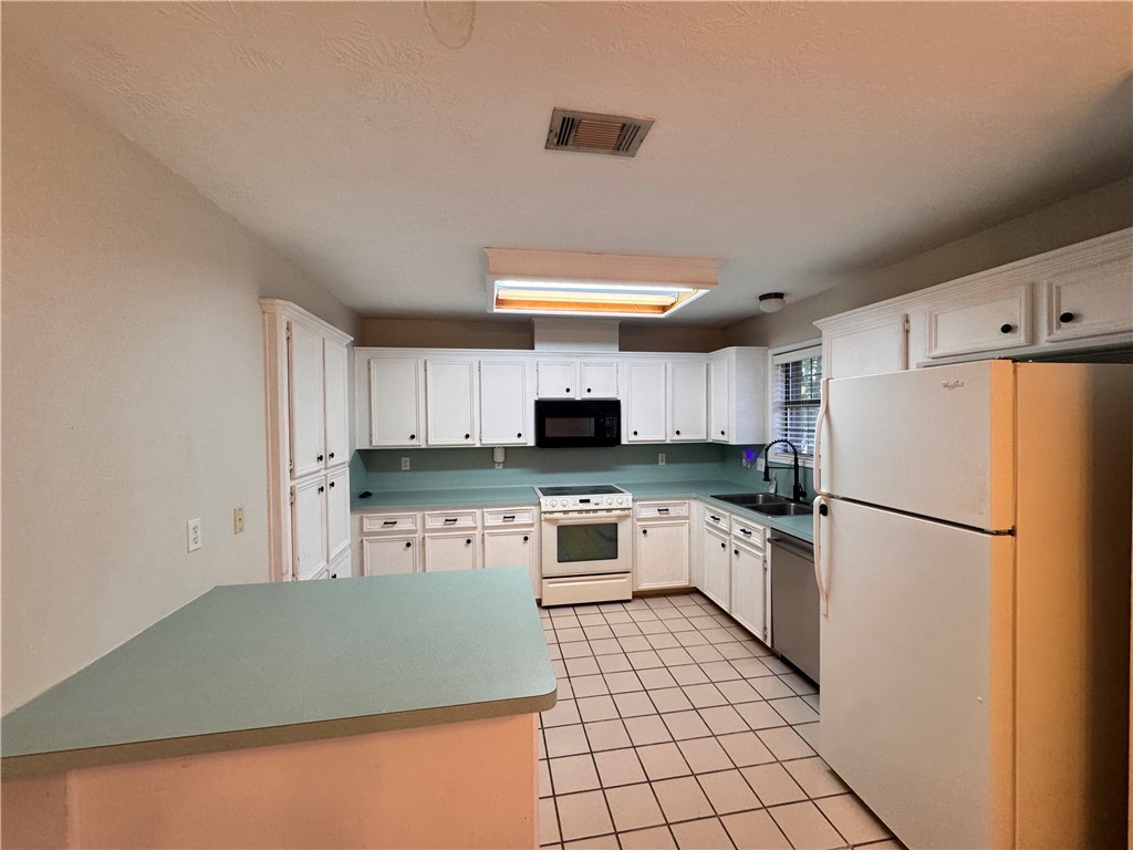 1204 Bayou Woods Drive College Station, TX 77840 - Photo 7 of 14 a kitchen with a refrigerator a stove top oven and white cabinets