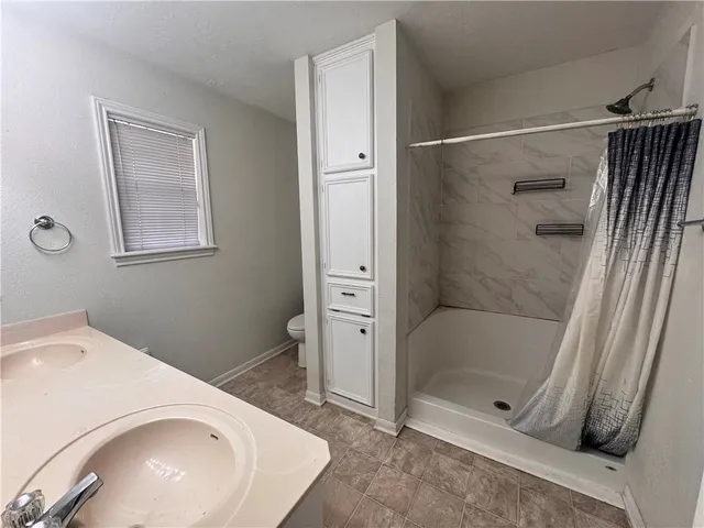 an empty room with ceiling fan and windows
