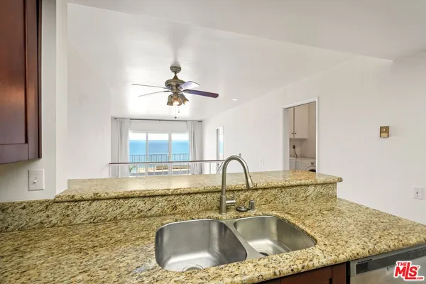 a kitchen with sink granite counter tops and a view of living room